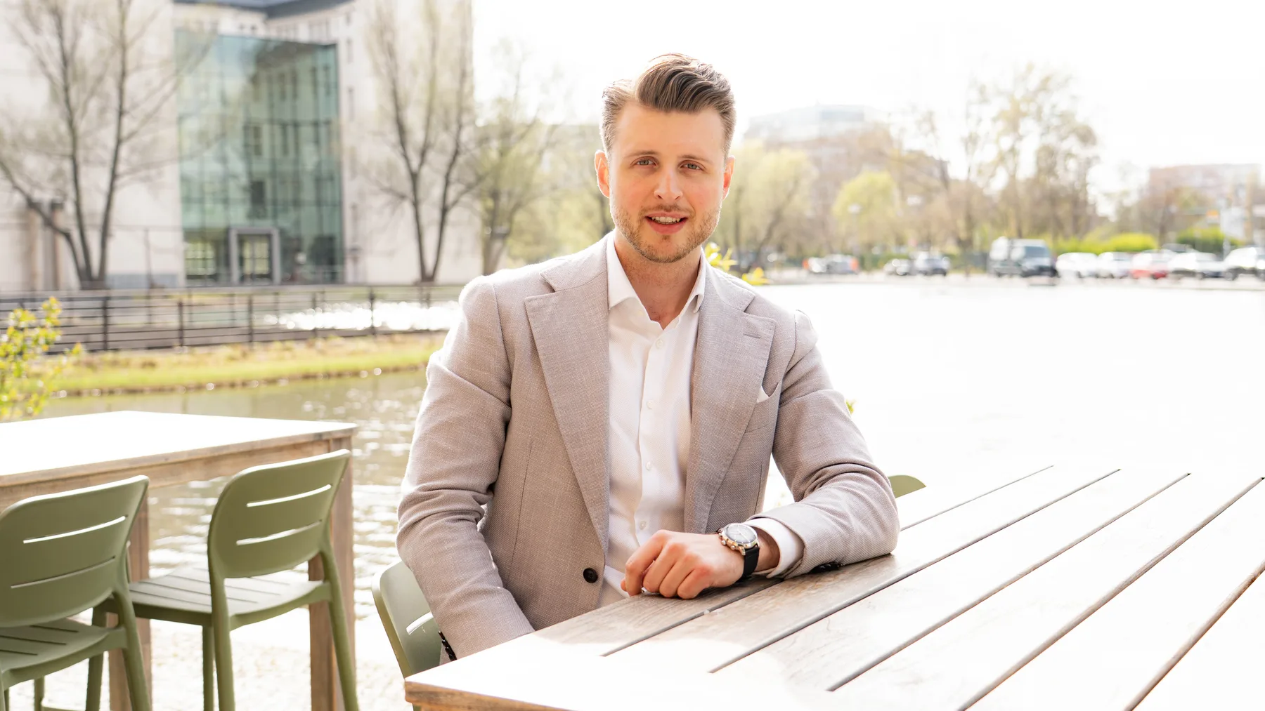 Julian Bilek im Gespräch an einem Tisch am Wasser in Berlin
