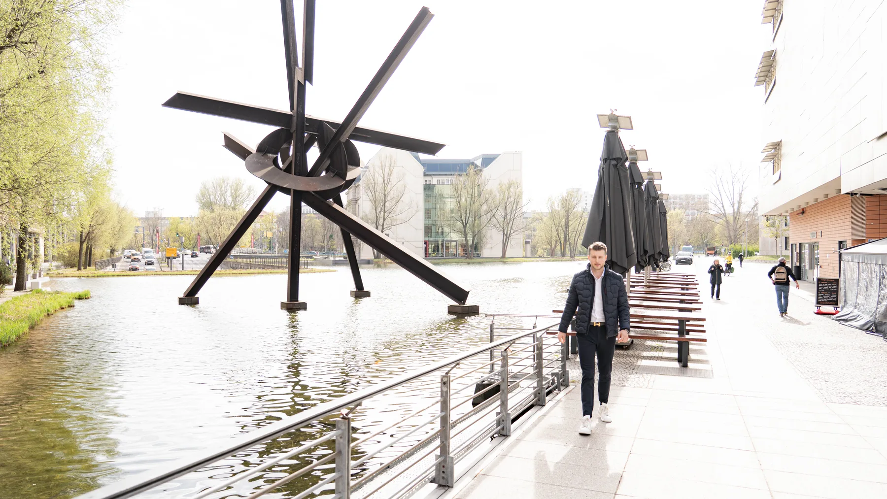 Julian Bilek geht an einem Wasserbecken am Potsdamer Platz entlang